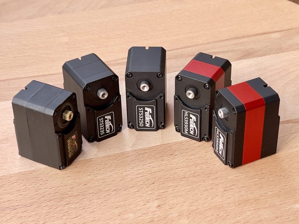 The five smart serial servos tested: STS3215, STS3235, STS3250, HLS3930M and HLS3950M lined up on a workbench