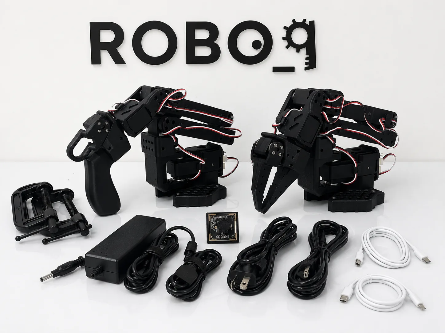 Everything in the black SO-ARM101 kit laid out: two arms, USB camera, power supplies, cables and clamps