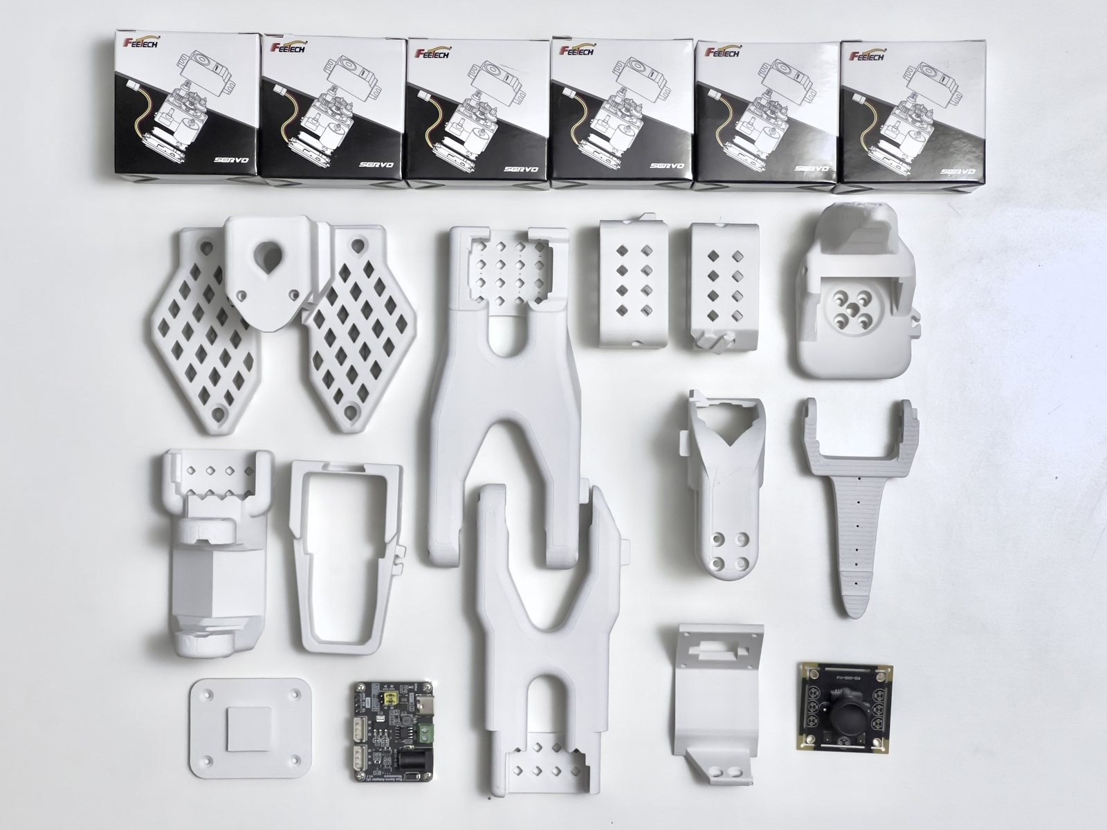 The follower arm: white printed parts, the gripper jaw, the camera module, its driver board and six servos.